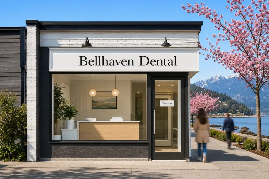 A small dental clinic called Bellhaven Dental in Ambleside, West Vancouver, on a spring morning, with a Welcome sign on the door, cherry blossom and the North Shore mountains behind.